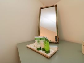 A bathroom countertop with green cream tubes and a mirror at Spring Cottage in York