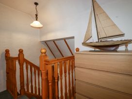 A landing with a staircase and a model sailboat on a chest of drawers at The Wedge in Mitchell near Summercourt