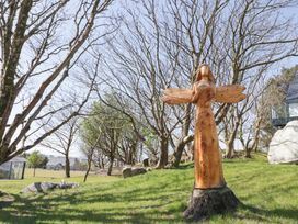 A wooden sculpture of a winged figure on grass with leafless trees in the background at Number 2 Dome in Derrybeg County Donegal