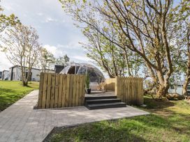 A clear dome structure on a wooden deck with steps surrounded by wooden fence and trees at Number 2 Dome in Derrybeg County Donegal