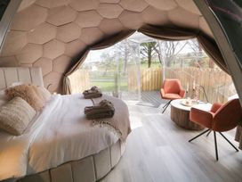 A bedroom with a bed, two orange chairs, a round table, and large windows at Number 2 Dome in Derrybeg County Donegal