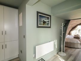 A bedroom with a bed visible through a hexagonal frame a coat stand a heating unit a framed picture and white cupboards at Number 2 Dome in Derrybeg County Donegal