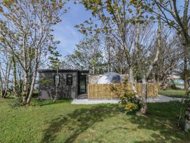 A small modern building with a fenced area and a dome structure behind trees on a grassy lawn at Number 2 Dome in Derrybeg County Donegal