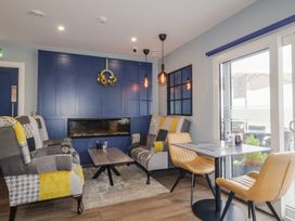 A sitting area with patchwork armchairs in front of a blue wall with a fireplace and a table with mustard chairs by a glass door at Number 2 Dome in Derrybeg County Donegal