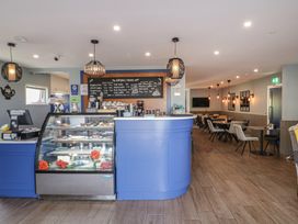 A cafe counter with a display case of desserts and a drinks menu above with tables and chairs in the background at Number 2 Dome in Derrybeg County Donegal