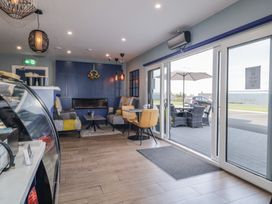 A cafe seating area with armchairs a table a fireplace and glass sliding doors leading to outdoor seating at Number 2 Dome in Derrybeg County Donegal