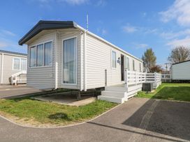 A white mobile home with steps and a small porch on a paved and grassy area at HW42 in Bognor Regis