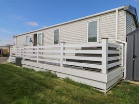 A mobile home with white railings and outdoor seating on a wooden deck at HW42 in Bognor Regis