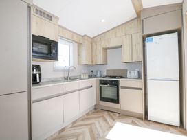 A kitchen with wooden cabinets a white refrigerator gas stove microwave and countertop appliances at HW42 in Bognor Regis