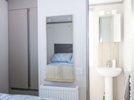 A bedroom with a wardrobe a mirror above a radiator and a pedestal sink with a mirror cabinet at HW42 in Bognor Regis