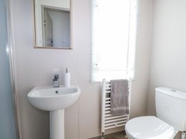 A bathroom with a sink pedestal mirror towel radiator and toilet at HW42 in Bognor Regis