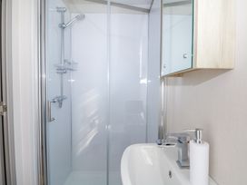 A bathroom with a shower enclosure a sink with a faucet and a soap dispenser at HW42 in Bognor Regis