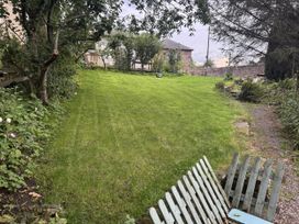 A garden with grass and trees at Yew Tree Cottage