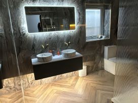 A bathroom with sinks, toilet, and mirror at Yew Tree Cottage