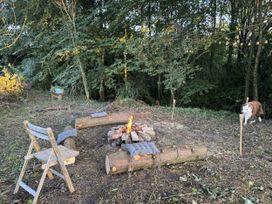 An outdoor fire pit area with seating and a dog at Yew Tree Cottage