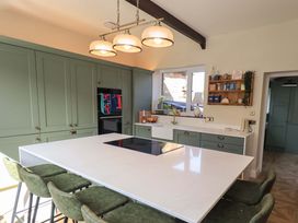 A kitchen with a central island and green cabinets at Yew Tree Cottage Mealsgate near Ireby