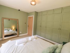 A bedroom with a bed and a mirror at Yew Tree Cottage Mealsgate near Ireby