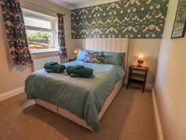 A bedroom with a bed and a bedside table at Yew Tree Cottage Mealsgate near Ireby