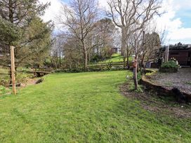 A garden with trees and a bird feeder at Yew Tree Cottage, Mealsgate near Ireby