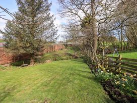 A garden with trees and grass at Yew Tree Cottage Mealsgate near Ireby