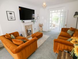 A living room with orange sofas a fireplace and a wall mounted TV at Burry House in Llanmorlais