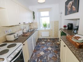 A galley kitchen with cream cabinets brown countertops and patterned tiled floor at Burry House in Llanmorlais