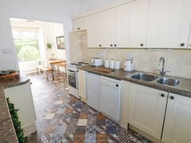 A kitchen with white cabinets appliances and a dining area with a wooden table and benches at Burry House in Llanmorlais