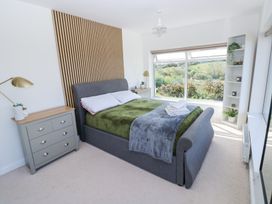 A bedroom with a gray bed and green blanket next to a window with a scenic view at Burry House in Llanmorlais