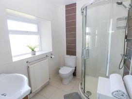 A bathroom with a shower enclosure toilet sink radiator and plant on the windowsill at Burry House in Llanmorlais