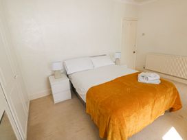 A bedroom with a double bed covered with an orange blanket and folded towels on top at Burry House in Llanmorlais