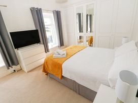 A bedroom with a bed, white dresser, television, and mirrored wardrobes at Burry House in Llanmorlais