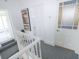 A hallway with blue carpet stairs white doors and a framed painting at Burry House in Llanmorlais