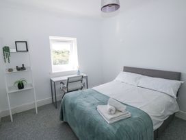 A bedroom with a bed folded towels a desk and chair a small white shelf by the window at Burry House in Llanmorlais