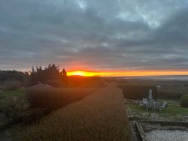 A sunset view with hedges and seating area at Burry House in Llanmorlais