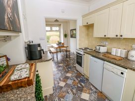 A kitchen with appliances and a dining table at Burry House Llanmorlais
