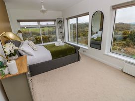 A bedroom with a bed and large windows at Burry House Llanmorlais
