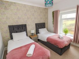A bedroom with two single beds and a bedside table at Burry House Llanmorlais