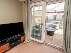 A living room with a television and a door leading to outdoor seating at 3 Hawk Place Moresby Parks near Whitehaven
