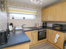 A kitchen with wooden cabinets black countertop a sink an oven a microwave and small plants at 56 Cherry Park Chalet in Chapel St Leonards