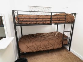 A bedroom with a metal bunk bed and brown bedding at 56 Cherry Park Chalet in Chapel St Leonards