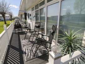 A porch with reclining chairs a small table and plants at 56 Cherry Park Chalet in Chapel St Leonards
