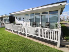 A front porch with chairs and decorative plants at 56 Cherry Park Chalet in Chapel St Leonards