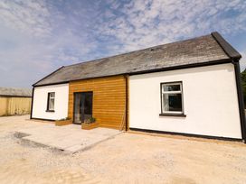 A house exterior with a wooden front door and planters at Teach Ti in Miltown Malbay