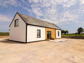 A house with a wooden front door and windows at Teach Ti in Miltown Malbay