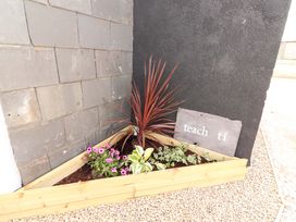 A garden planter with flowers and a sign at Teach Ti in Miltown Malbay