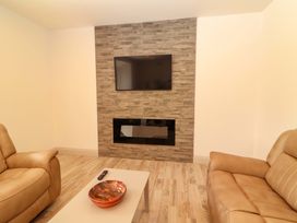 A living room with a TV mounted on a wall and a fireplace at Teach Ti in Miltown Malbay