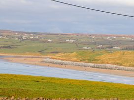 A beach scene with people and hills in the distance at Teach Ti in Miltown Malbay