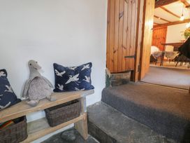 A wooden bench with cushions and a stuffed toy next to a step leading to a room with wooden furniture at Penygriusiau in Barmouth