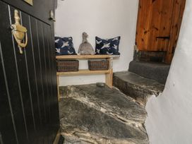 A small entrance area with stone steps wooden door and a bench with cushions and baskets at Penygrisiau in Barmouth