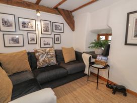 A corner seating area with a dark sofa and cushions beside a small black table with a plant and magazines at Penyrisiau in Barmouth